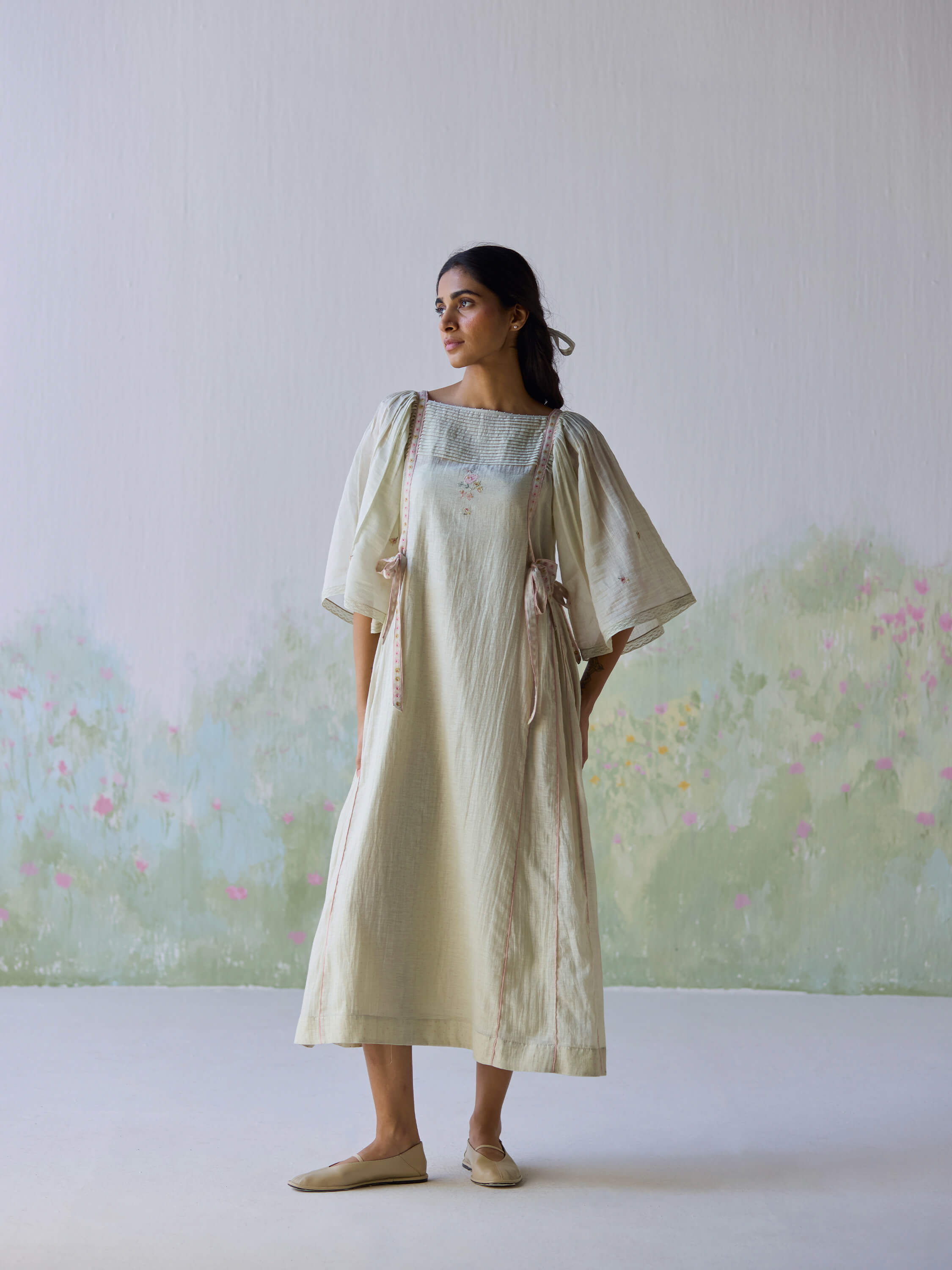 Elegant woman in Amore Midi Dress against floral backdrop.