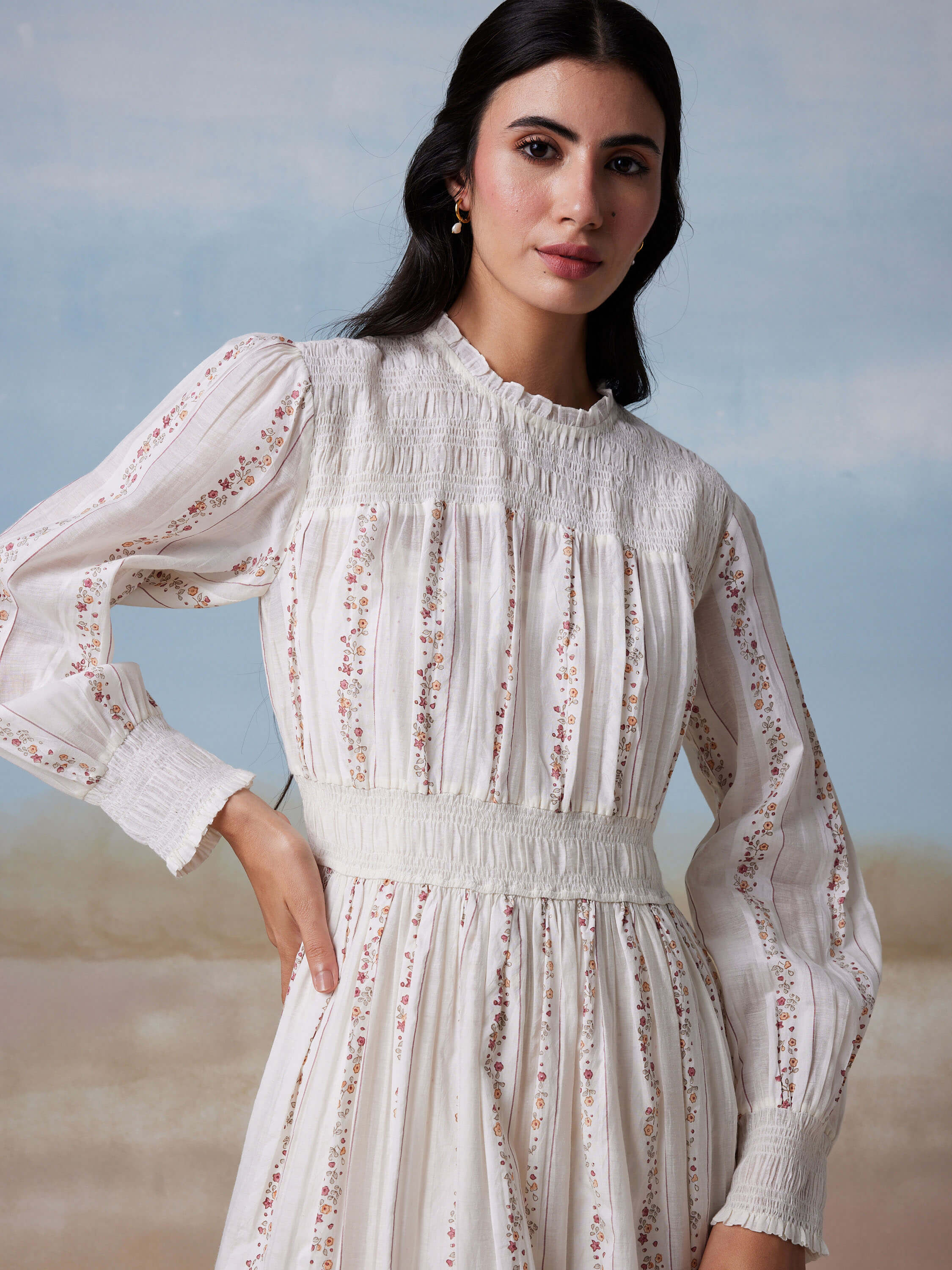 Woman in floral white dress with long sleeves.