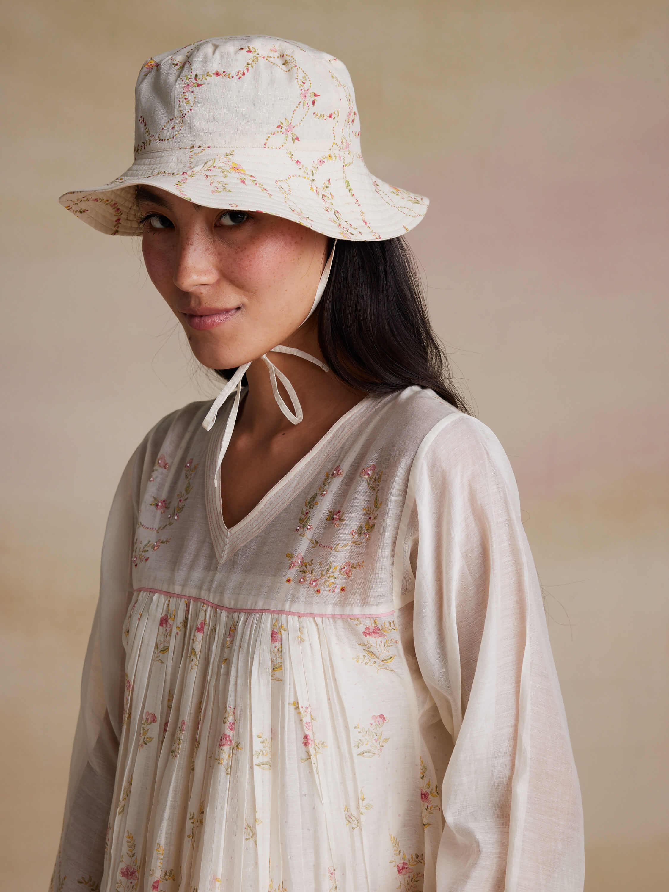 Woman in embroidered blouse and floral bucket hat.