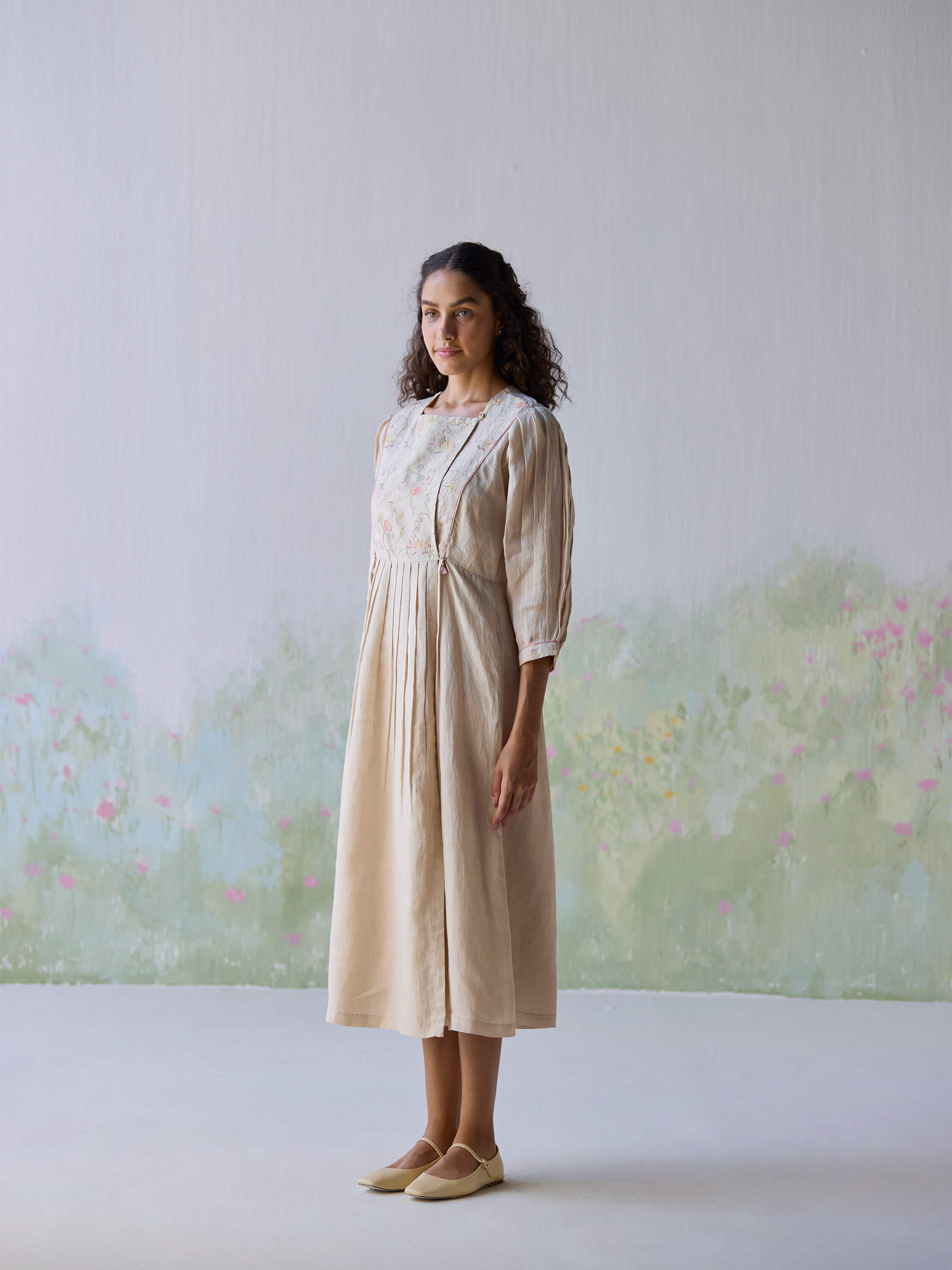 Model wearing Golden Days Linen Dress against a pastel floral background.