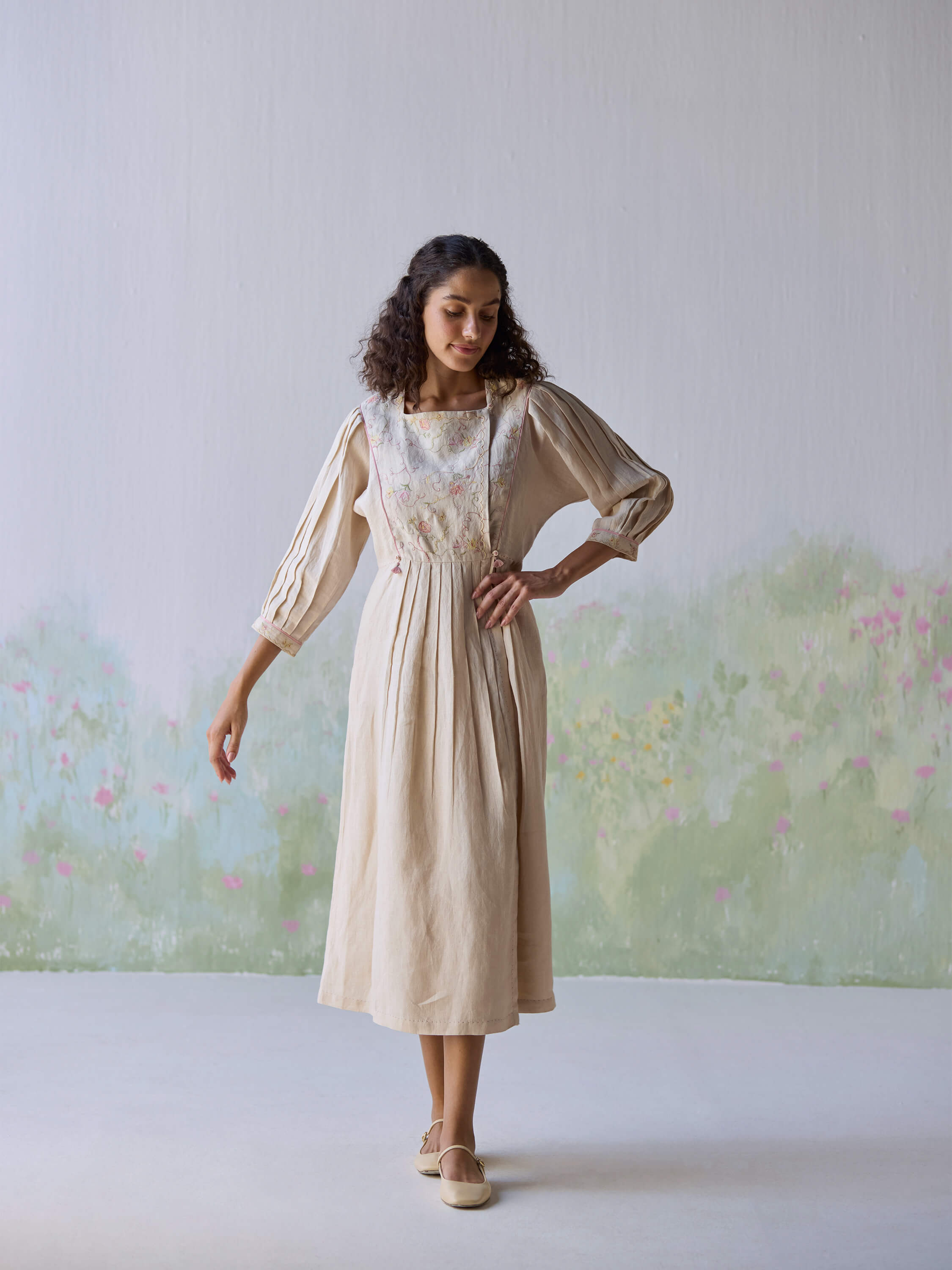 Model wearing Golden Days Linen Dress in a pastel floral setting.