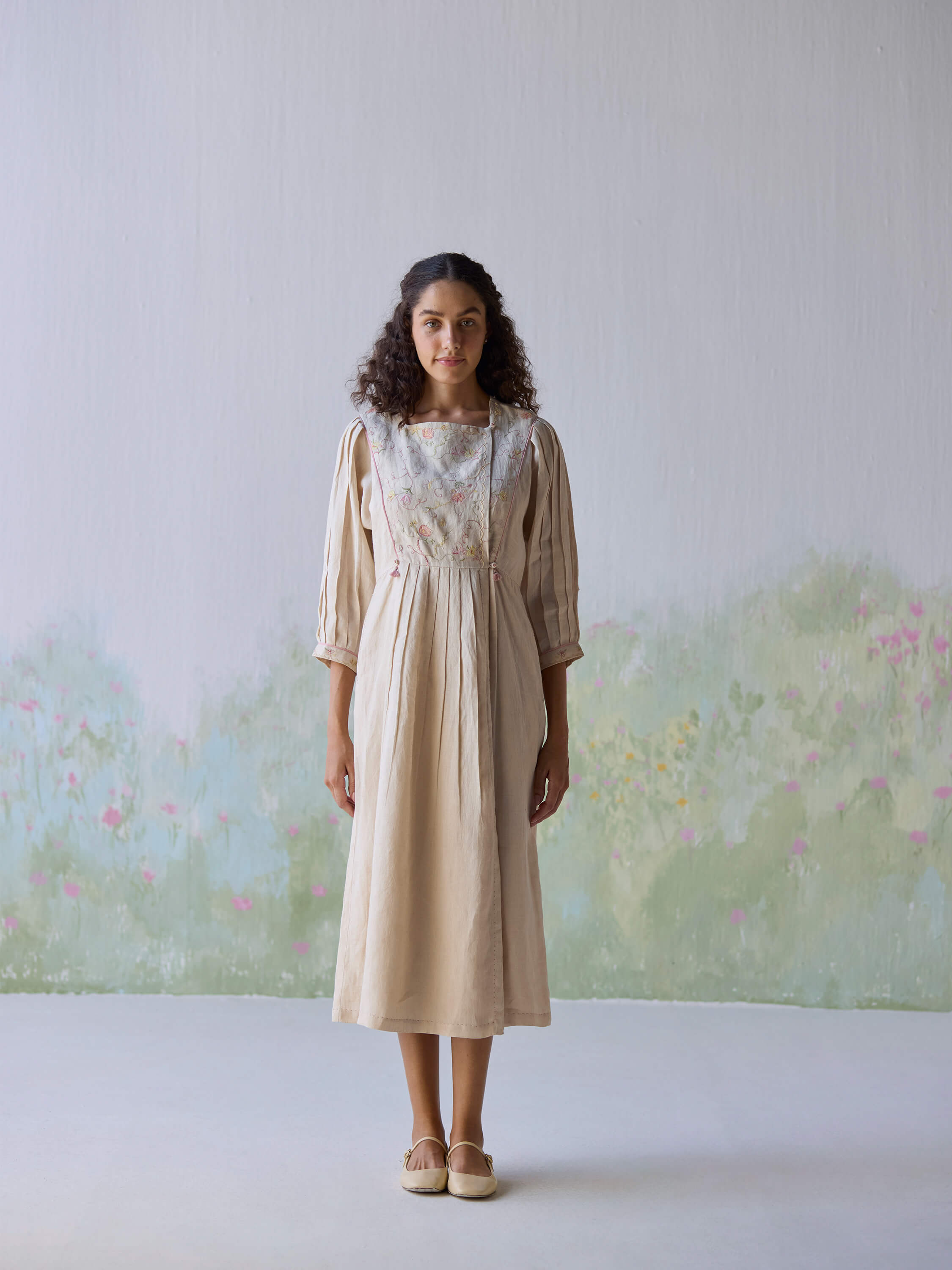 Elegant woman in Golden Days Linen Dress against floral background.