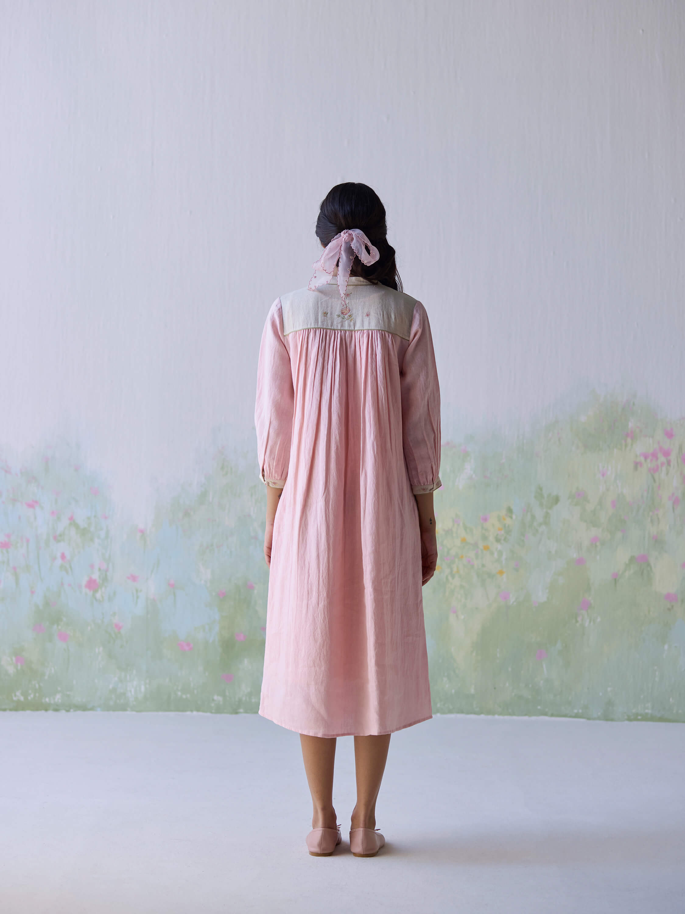 Woman wearing pink linen dress with garden background.