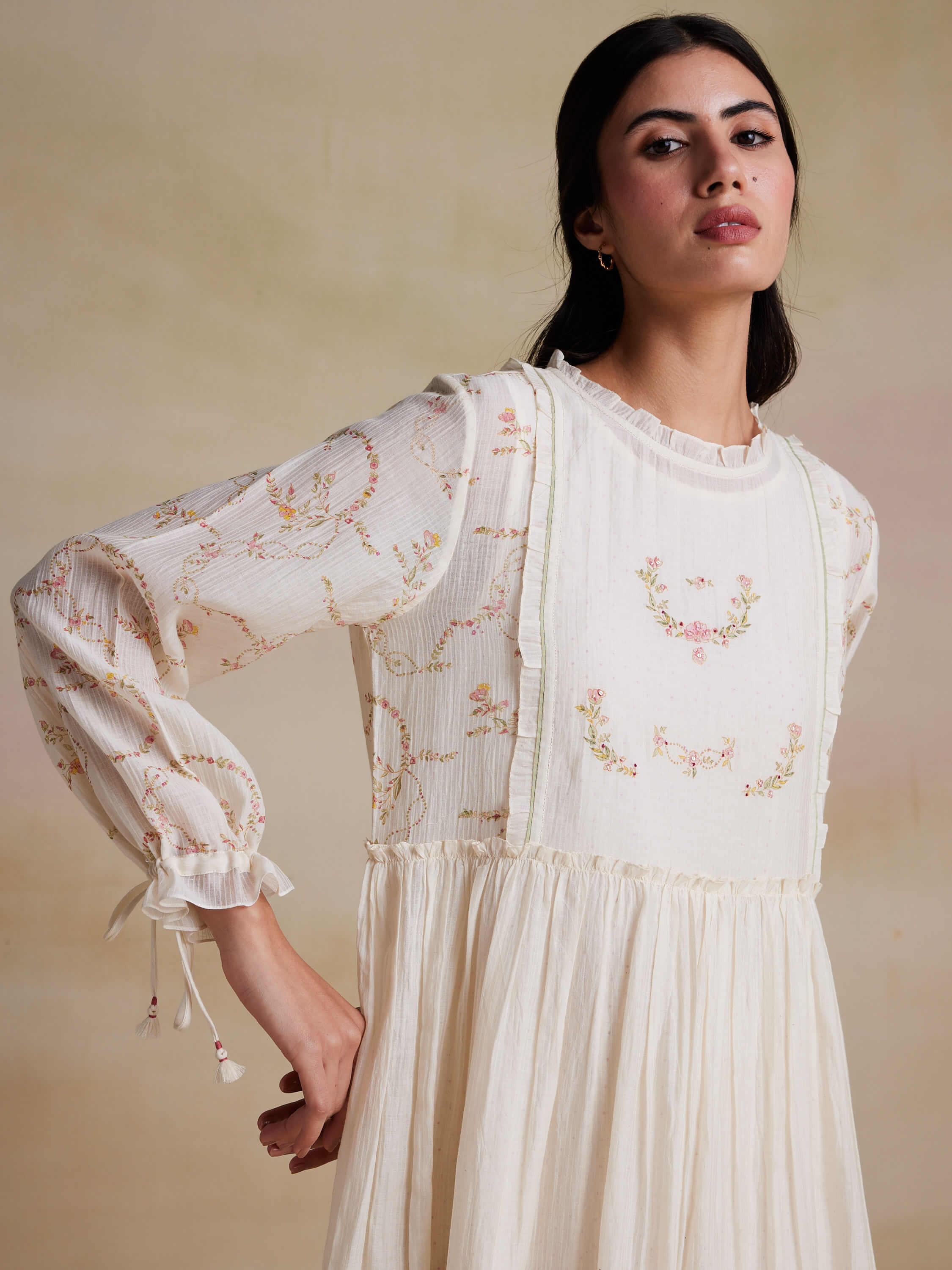 Woman in white, floral-embroidered dress posing fashion portrait.