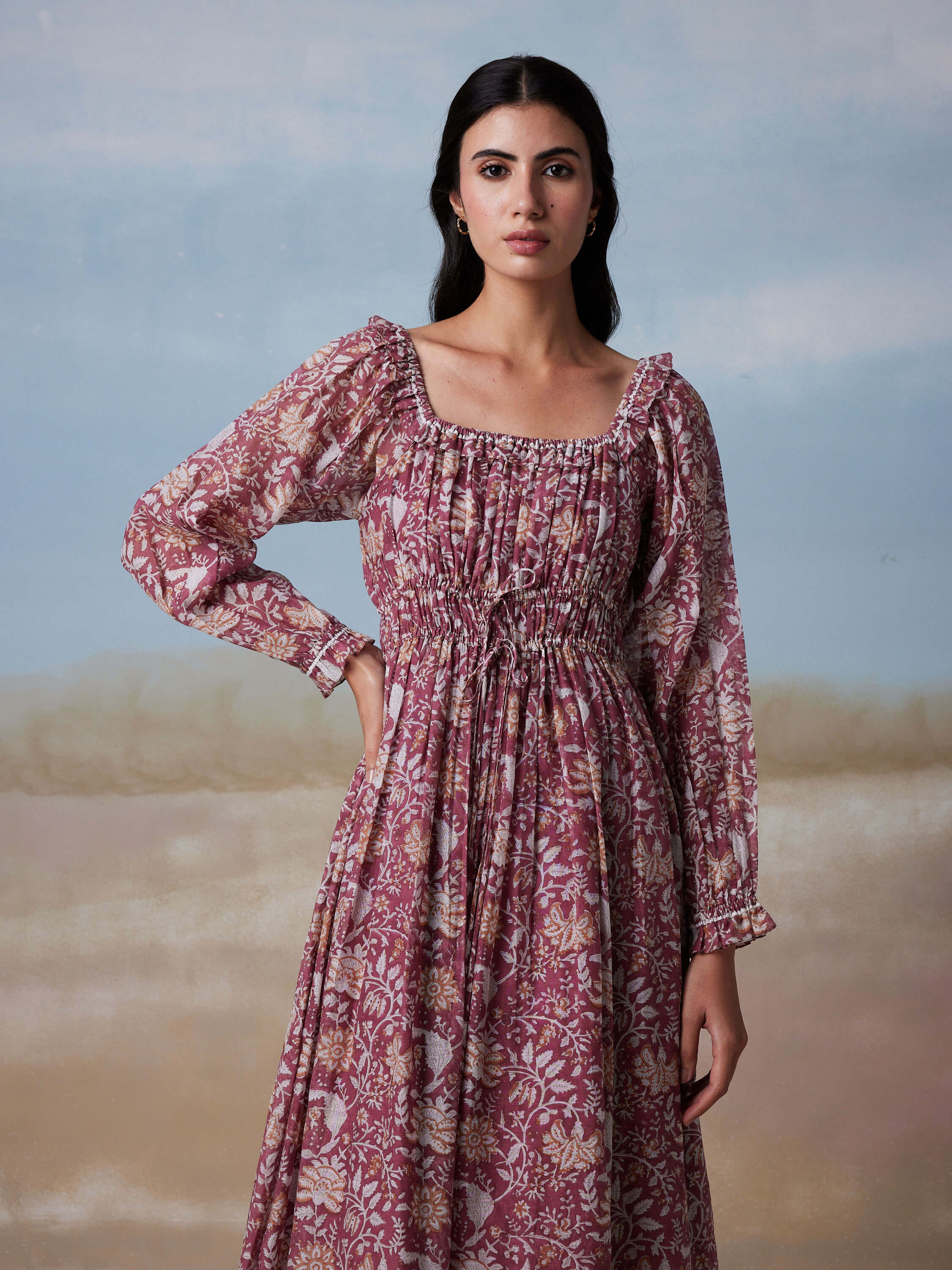 Woman in floral long-sleeve dress against a soft gradient background.