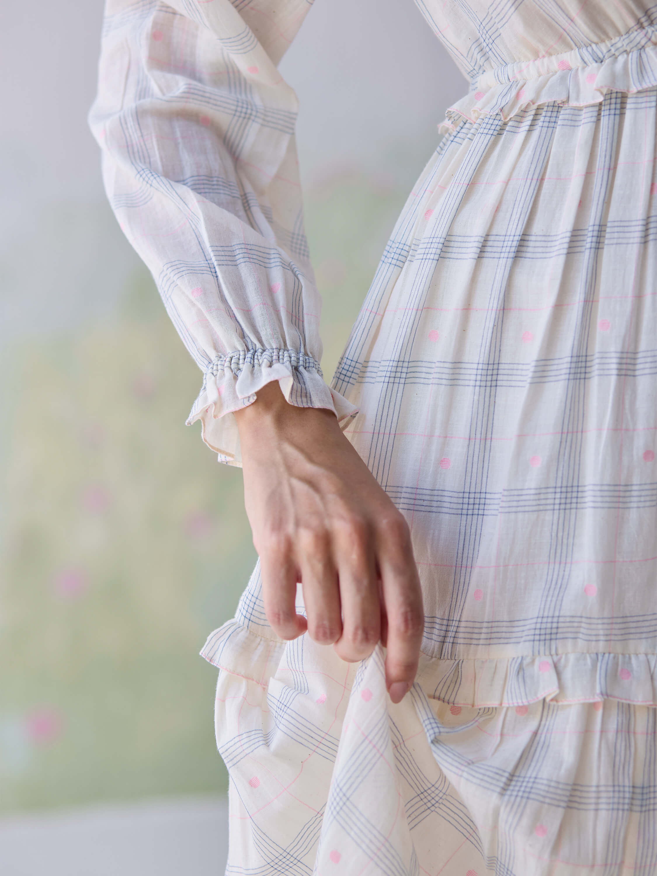 Close-up of hand on Paperdots Wrap Dress with pastel plaid pattern.