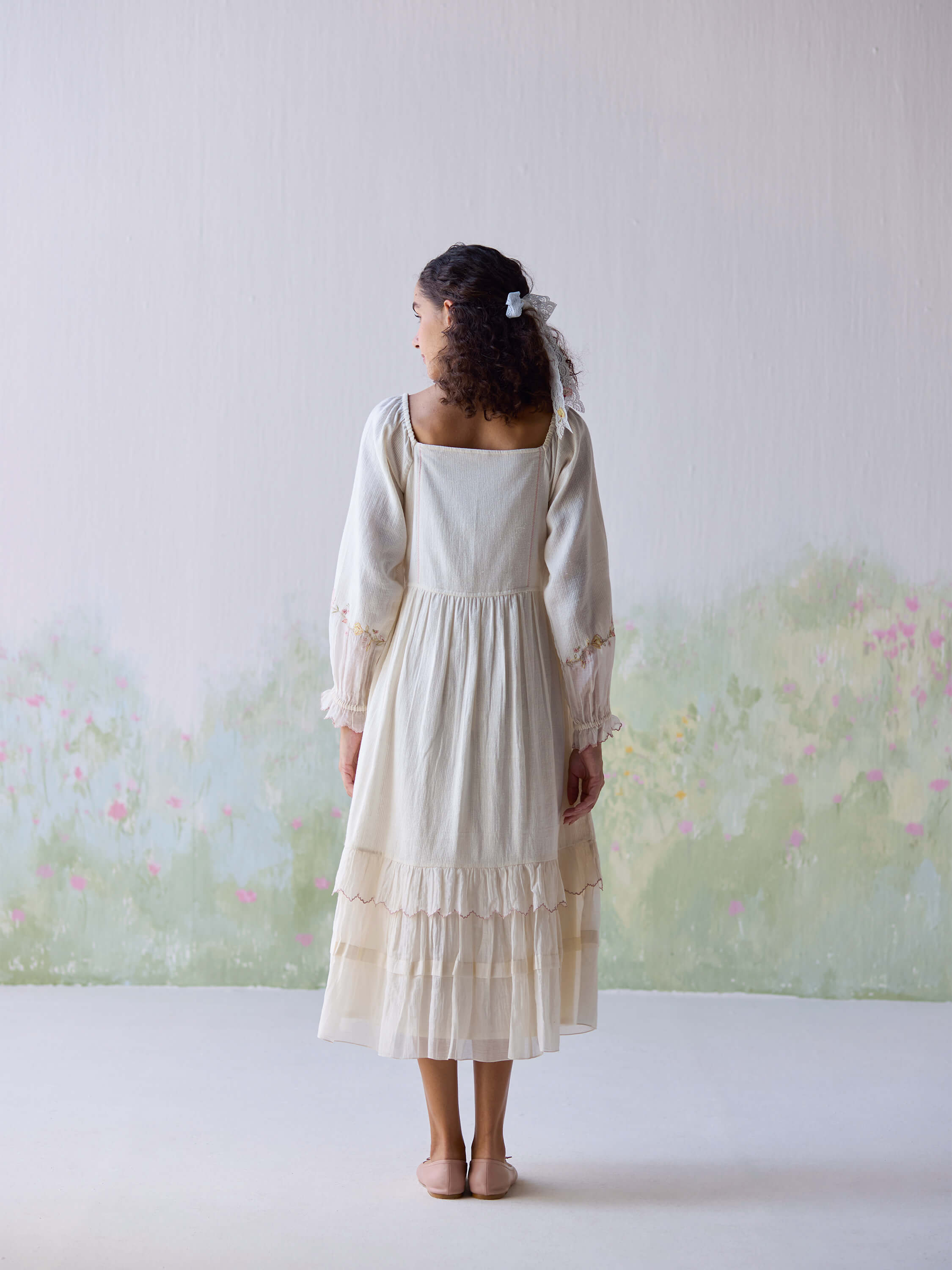 Elegant woman wearing Verona Midi Dress, back view, soft pastel background.