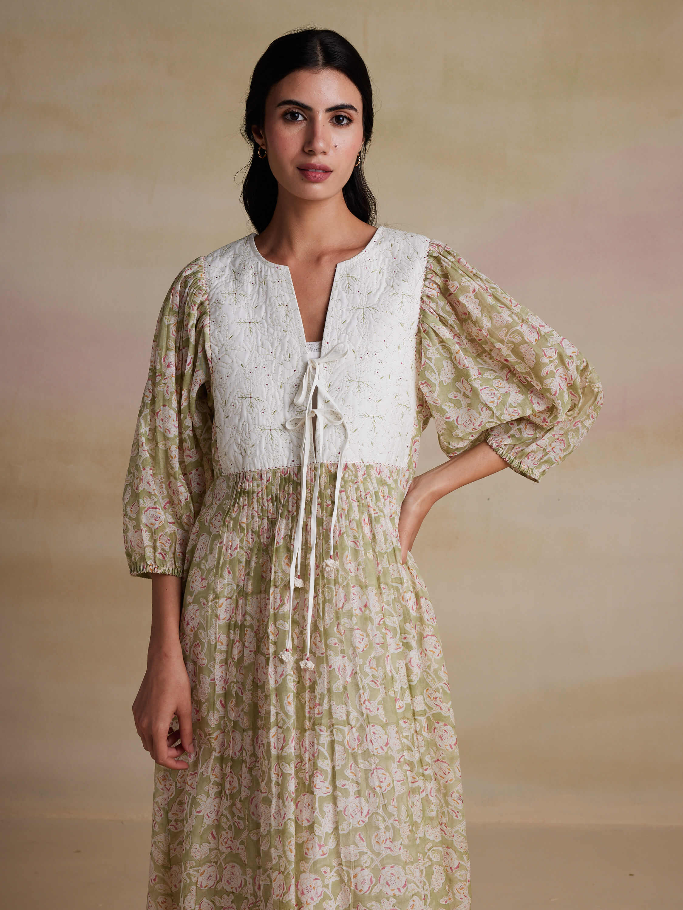 Woman in white floral dress with puffy sleeves against neutral background.