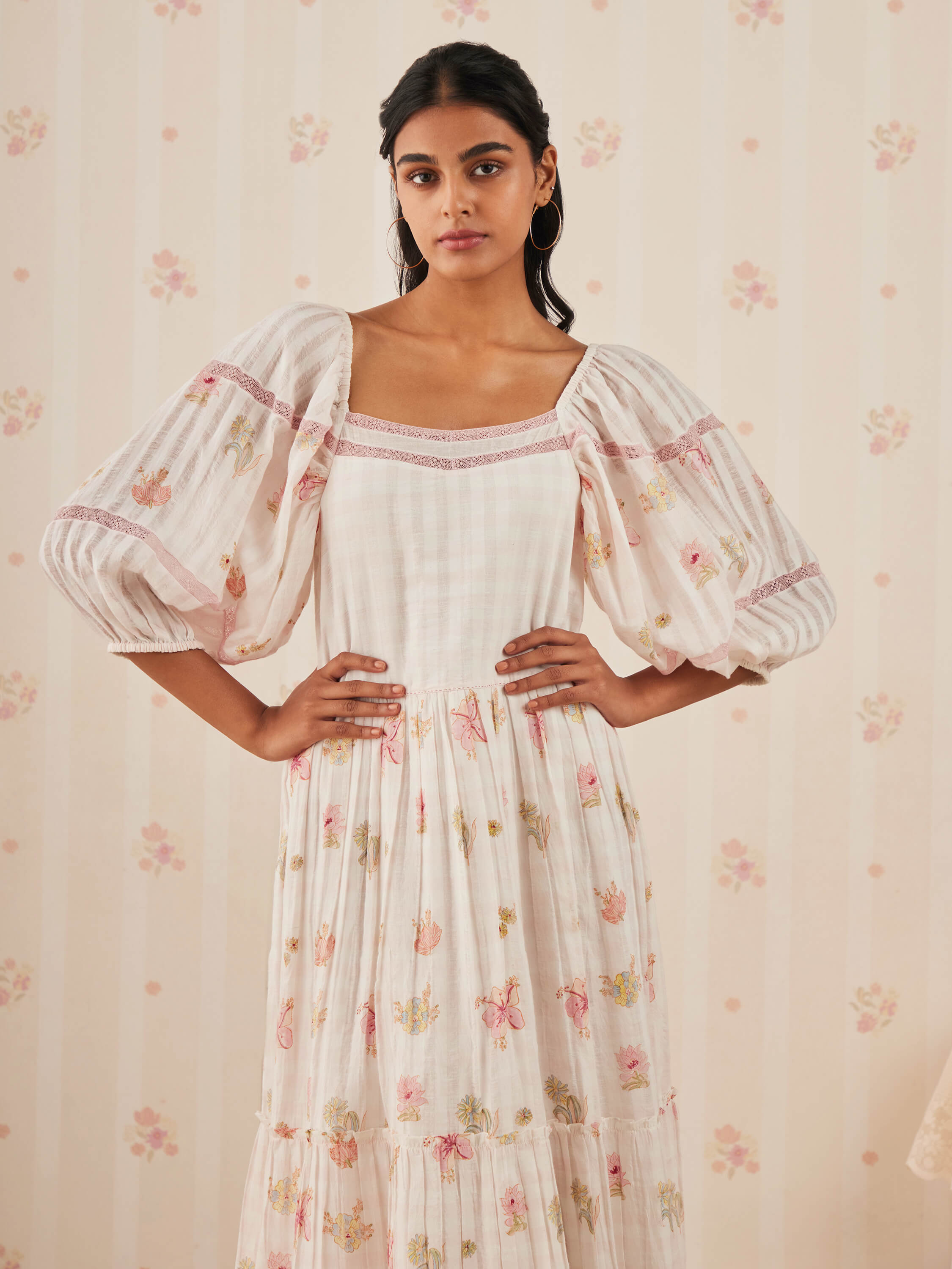 Woman in floral printed dress with puffy sleeves posing confidently.