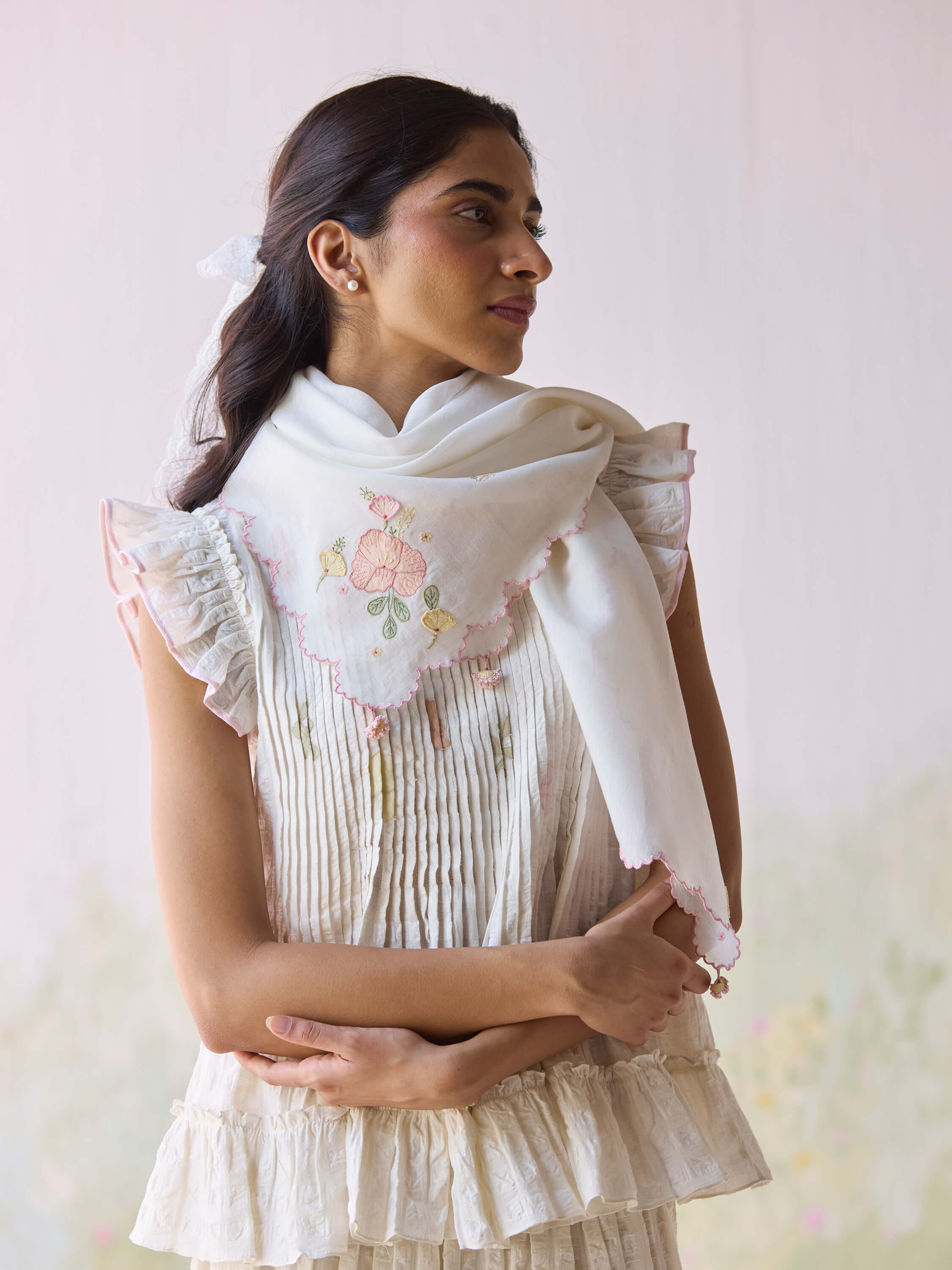 Woman in embroidered white scarf and ruffled dress looking sideways