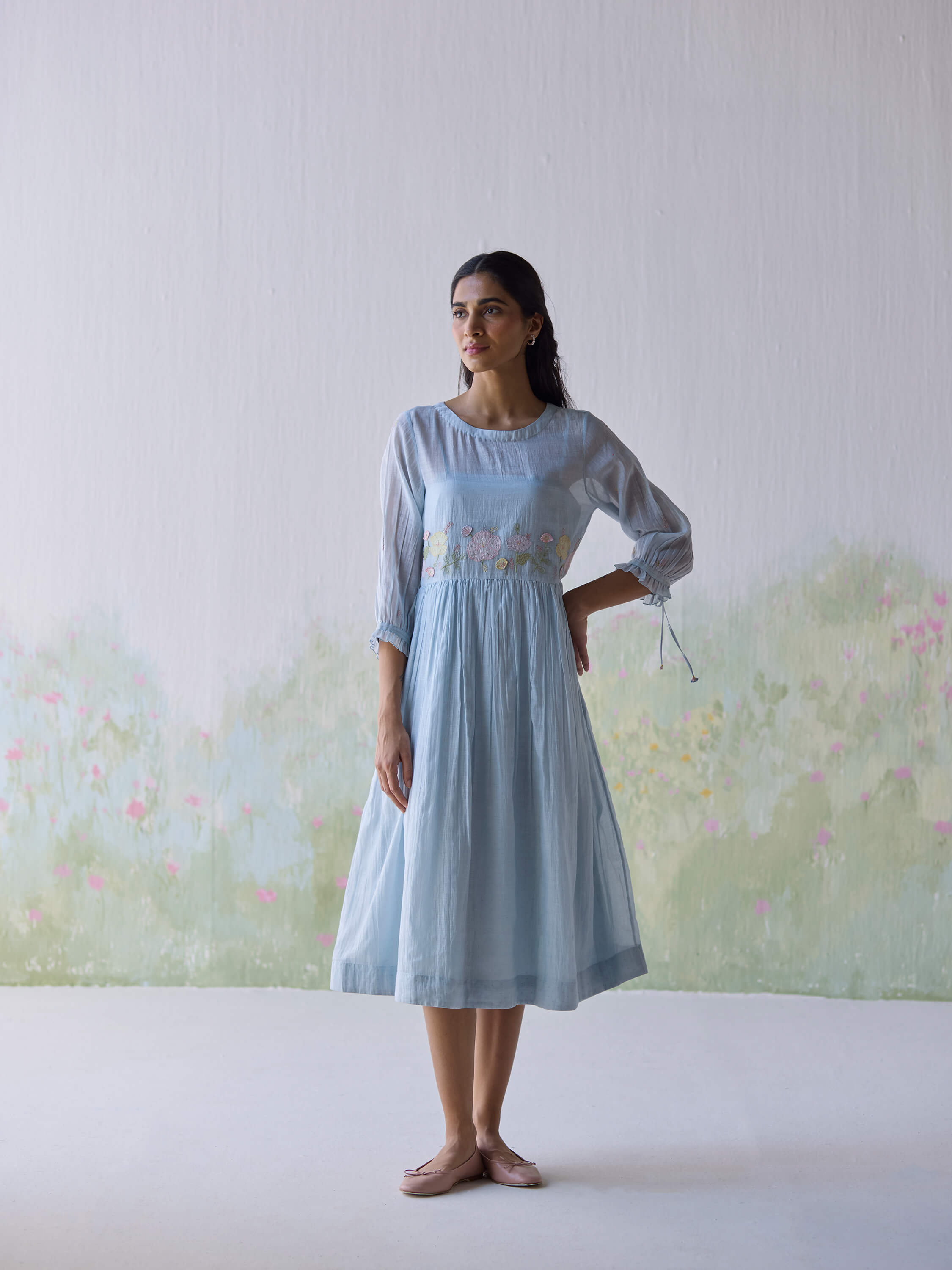 Woman in light blue dress with floral embroidery.