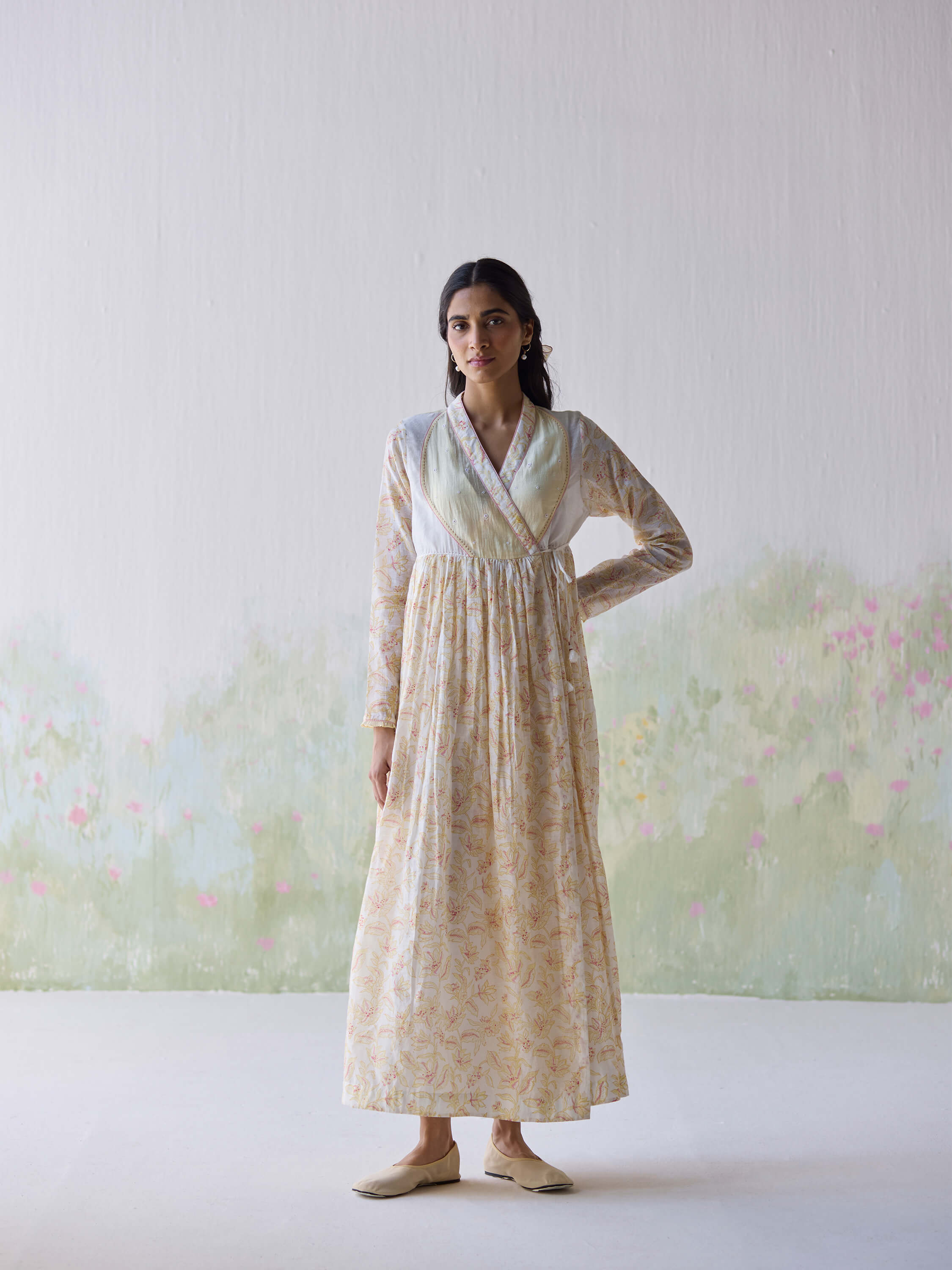 Woman wearing a long floral dress in a minimalist setting.