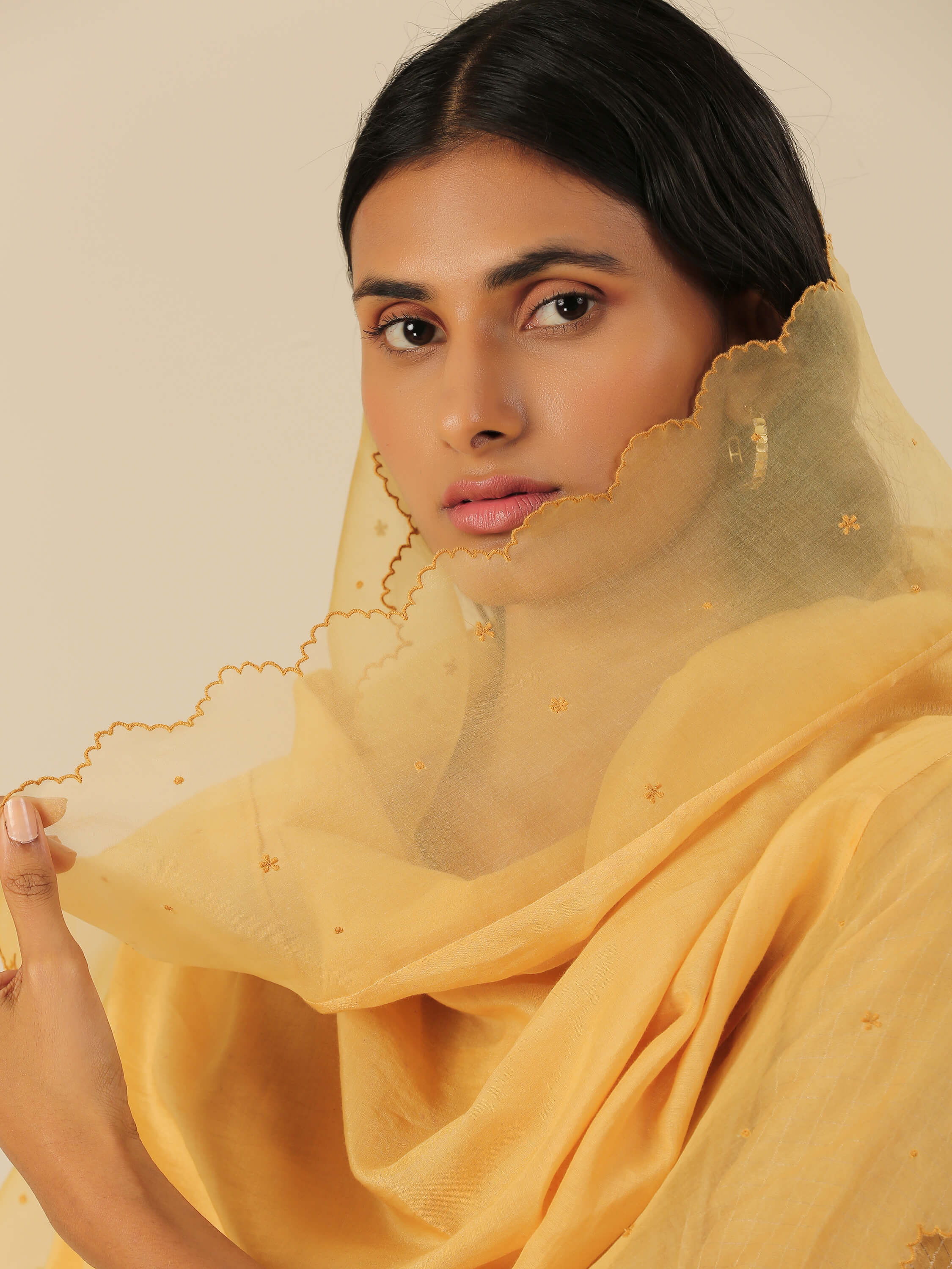 Woman in a yellow scarf, close-up portrait with soft gaze.