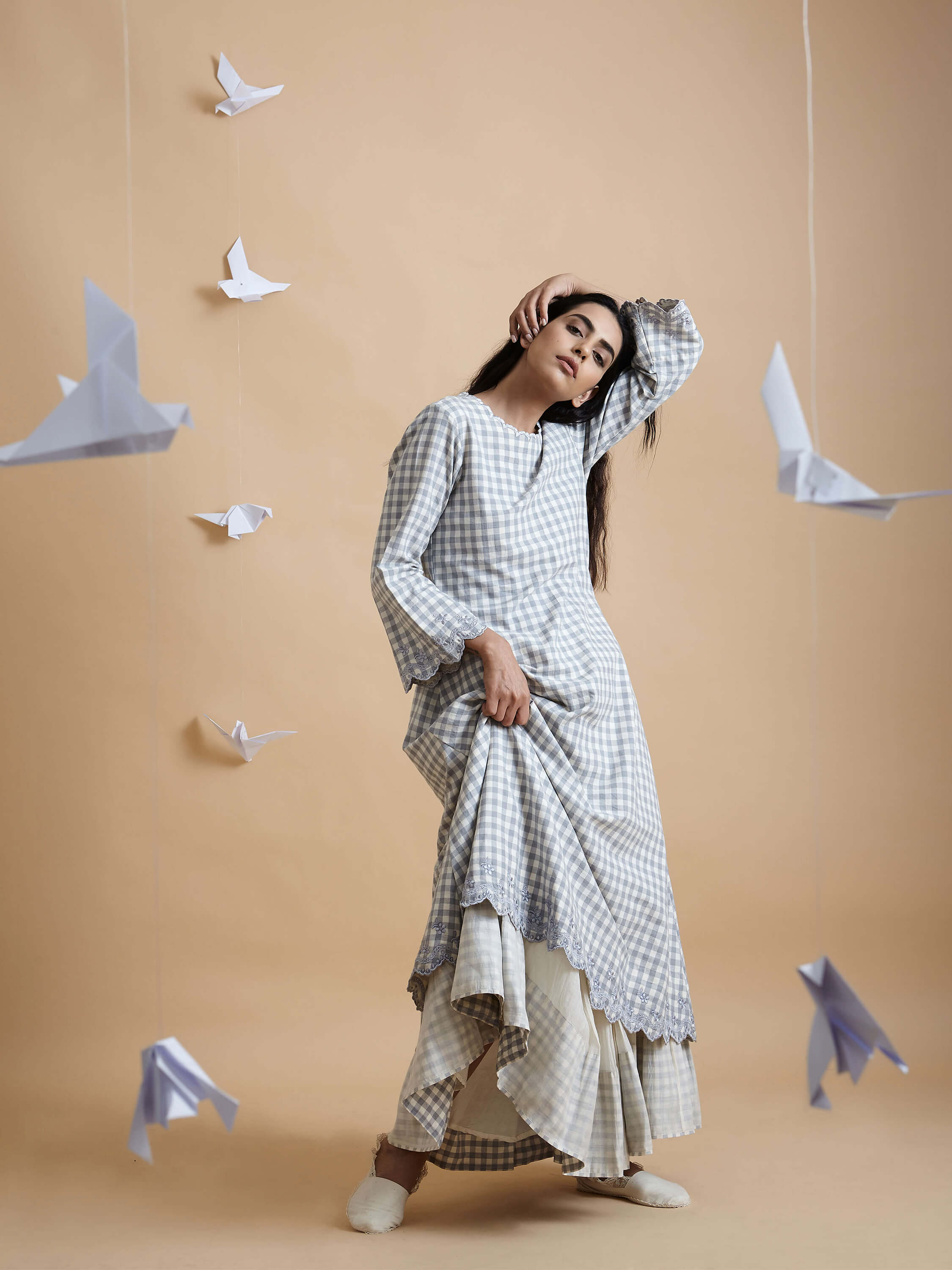 Woman in checkered dress posing with origami birds background.