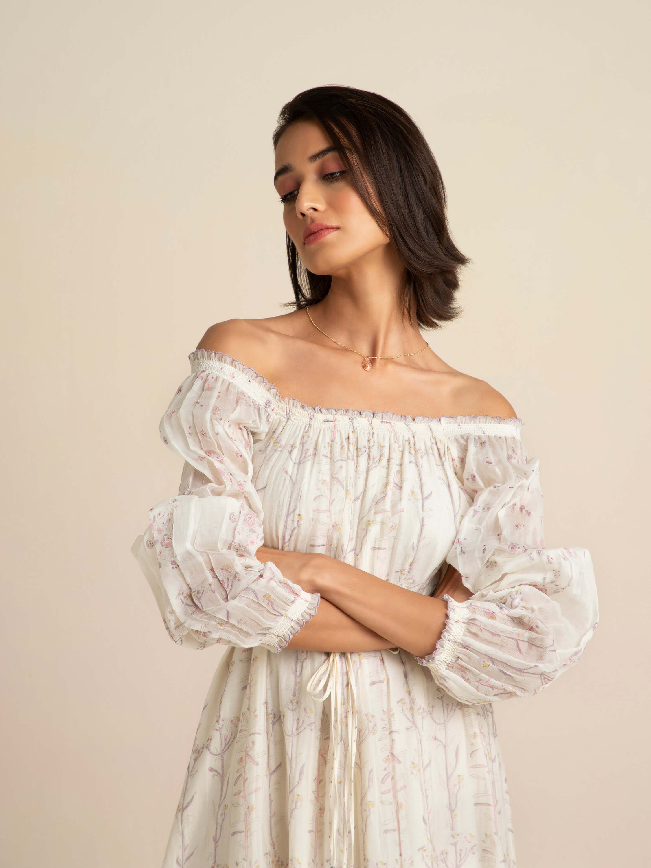 Woman in off-shoulder floral dress posing confidently.