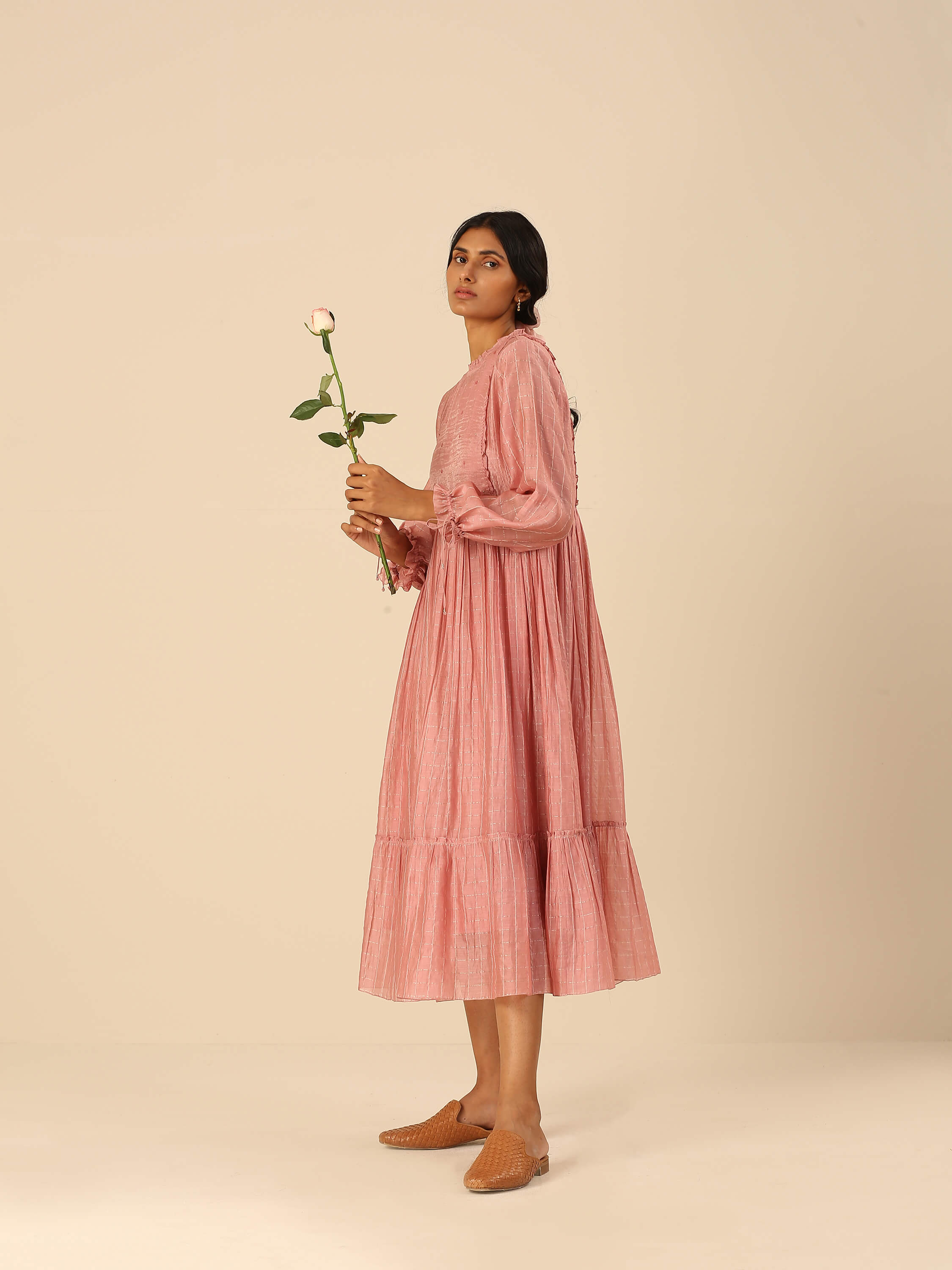 Woman in pink long dress holding a rose flower.