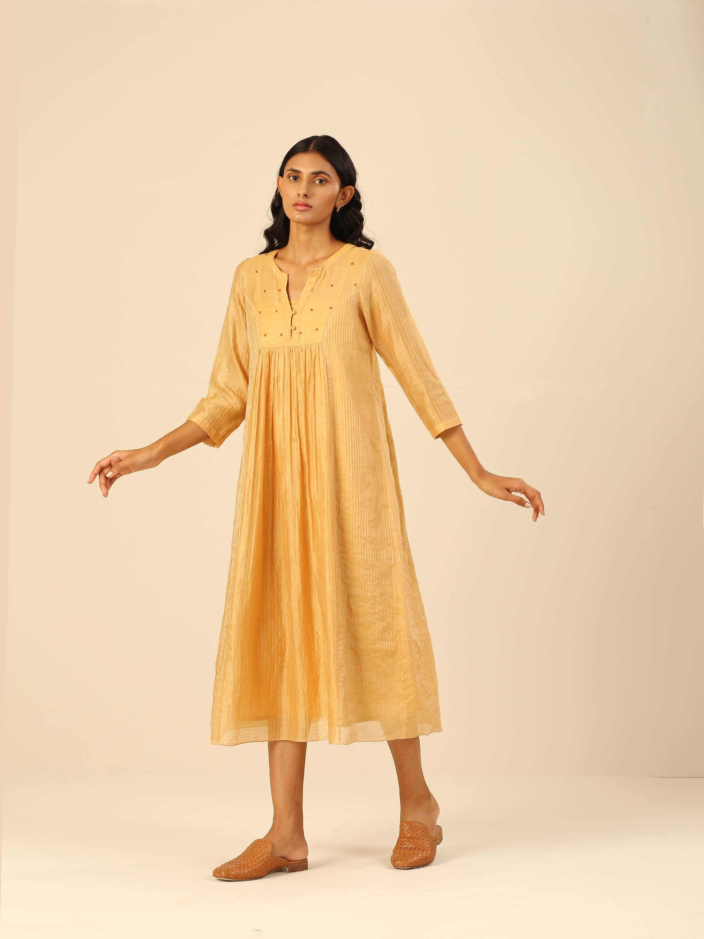 Woman wearing a yellow midi dress with three-quarter sleeves.