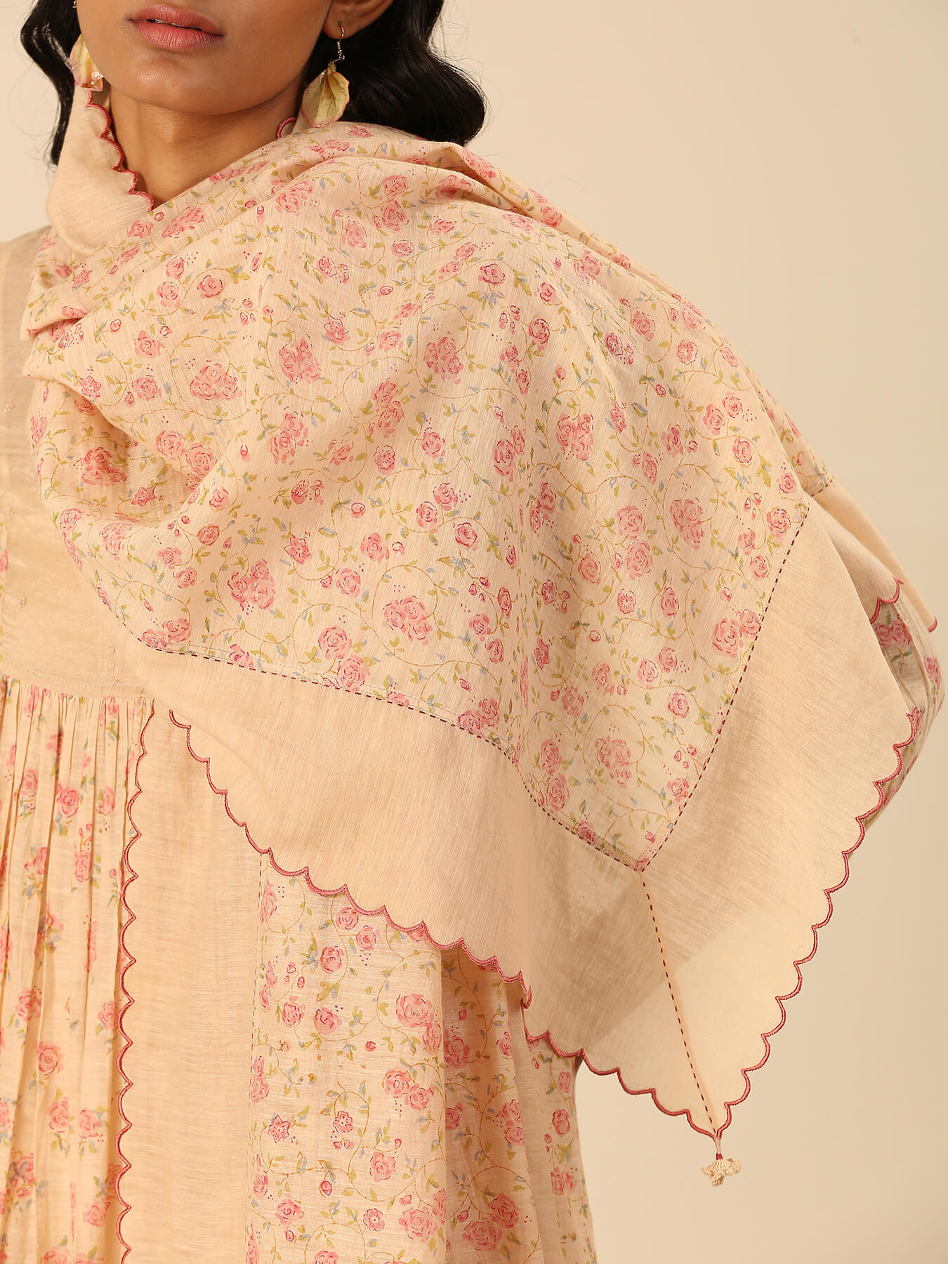 Woman wearing a floral embroidered shawl with scalloped edges.