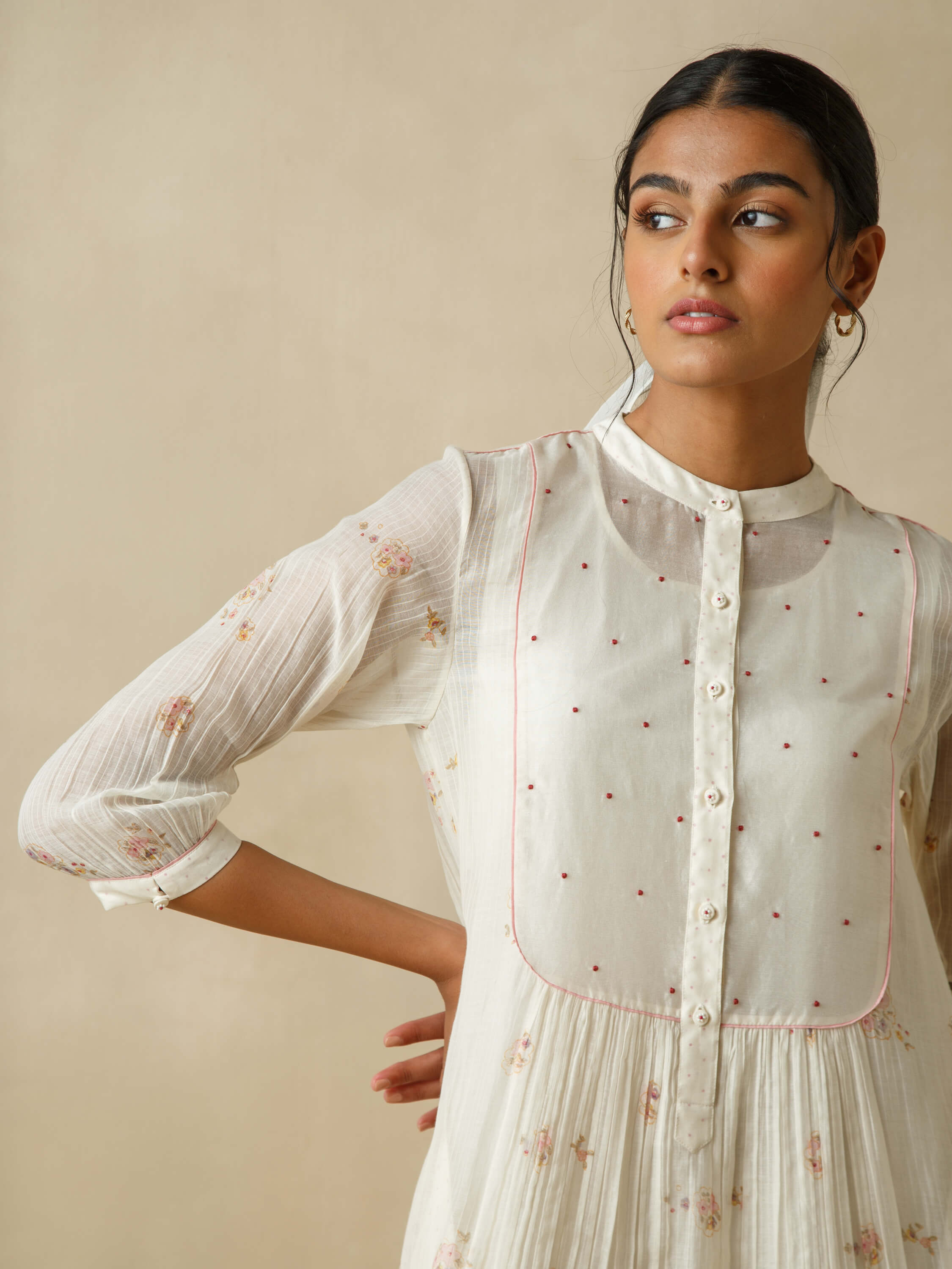 Woman in elegant white dress with floral embroidery.