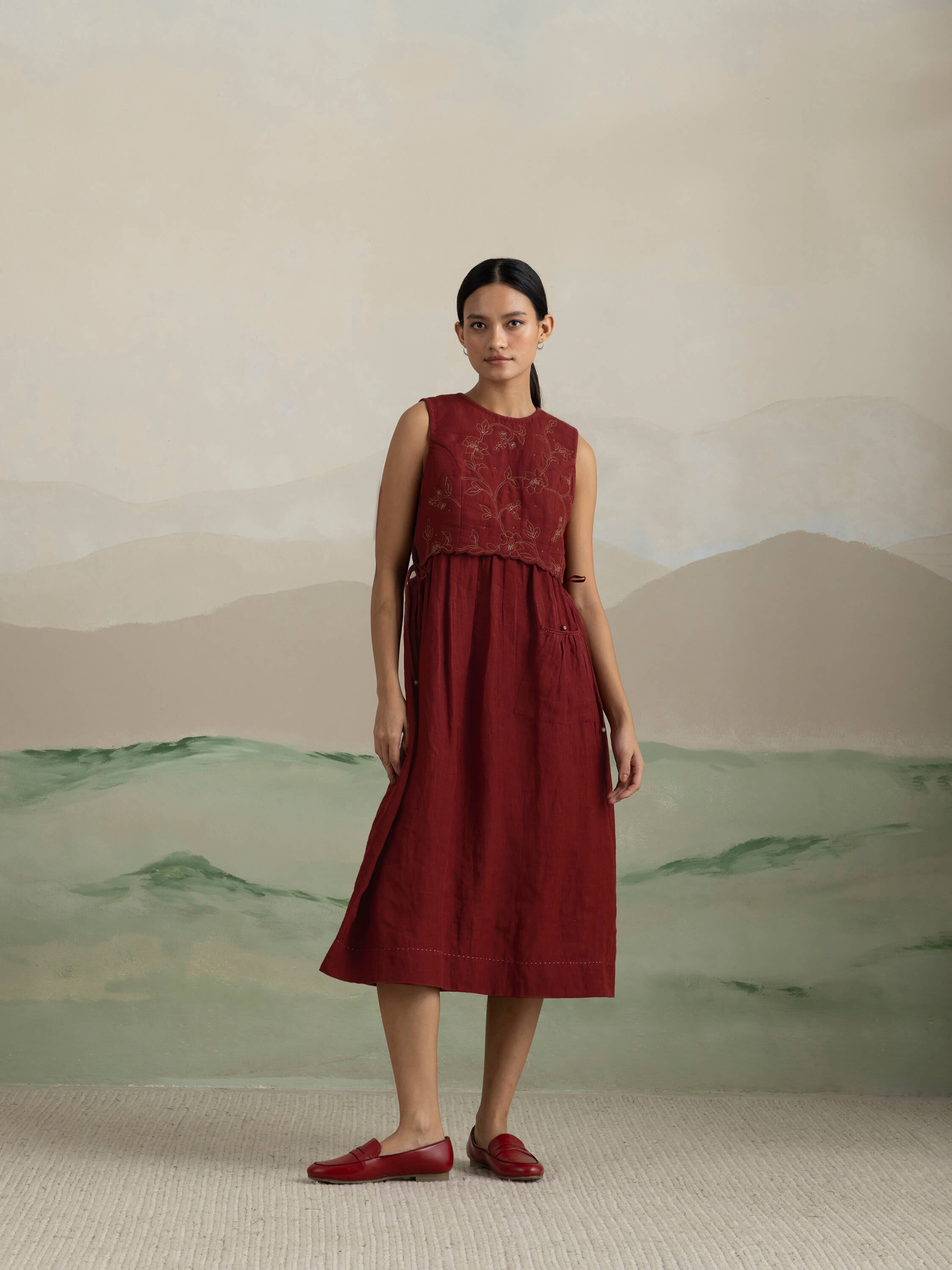 Woman in elegant red dress standing against abstract painted background.