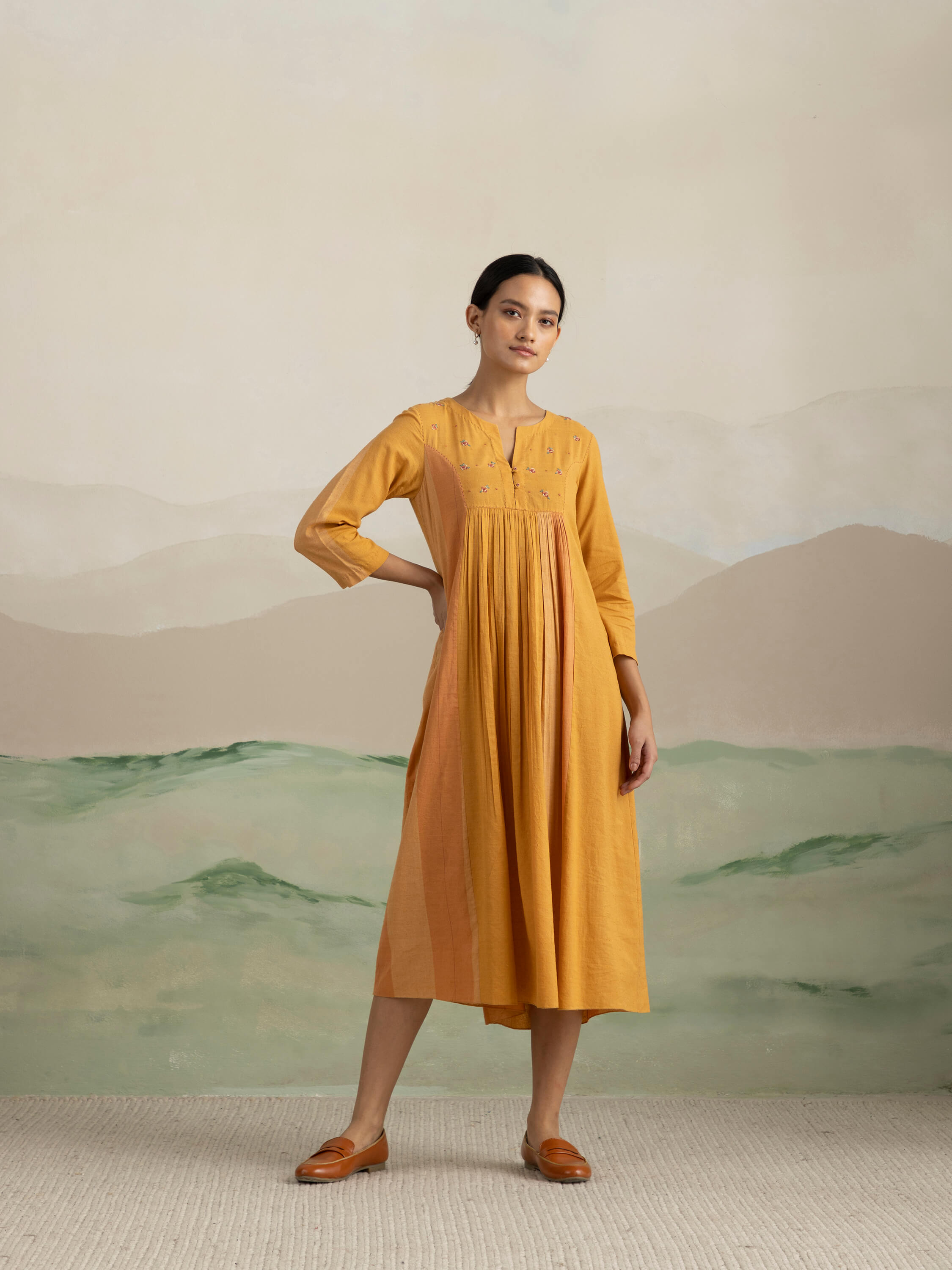 Woman wearing a yellow dress posing against a neutral background