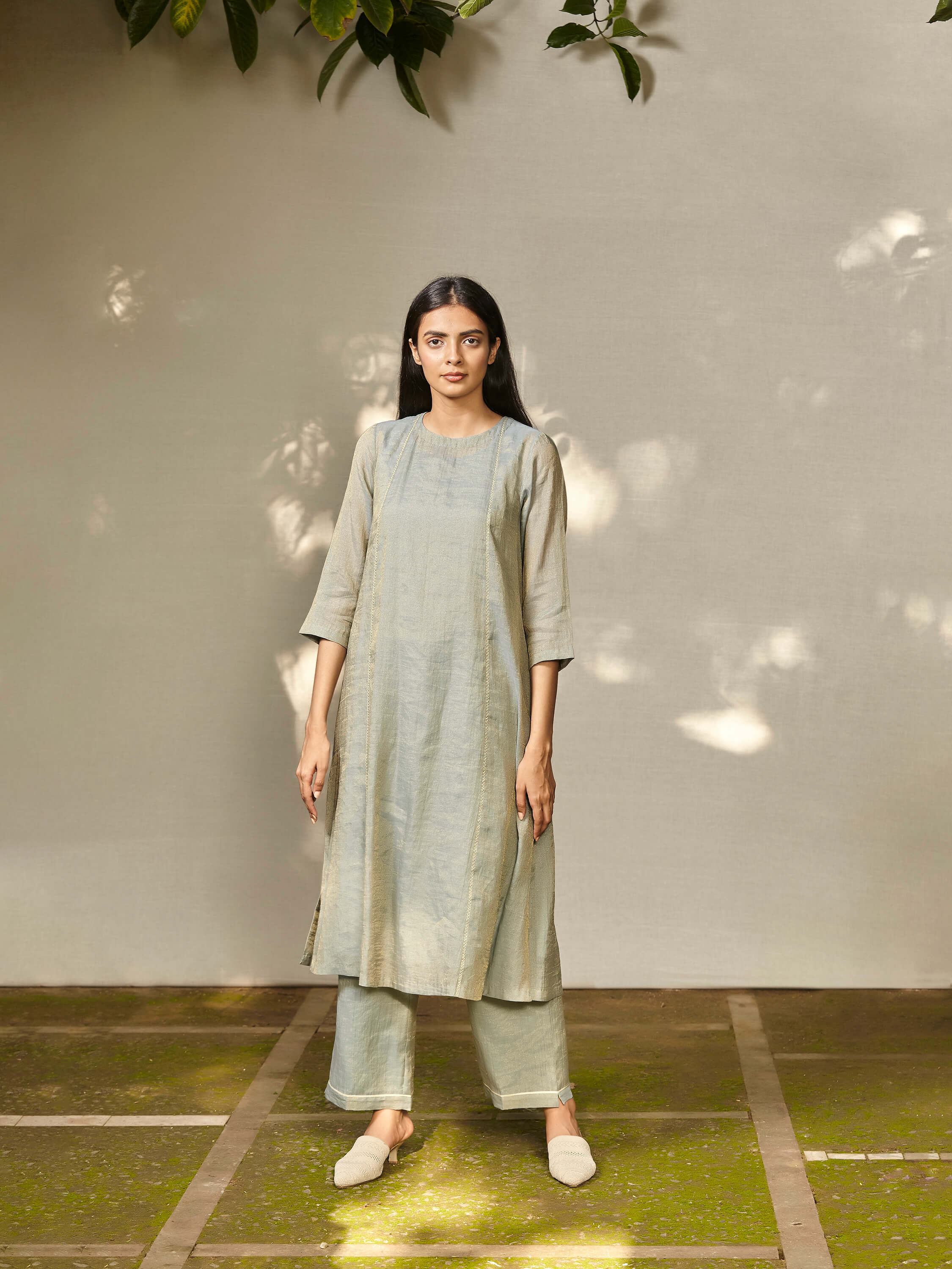 Woman in light blue ethnic long kurta and pants standing outdoors