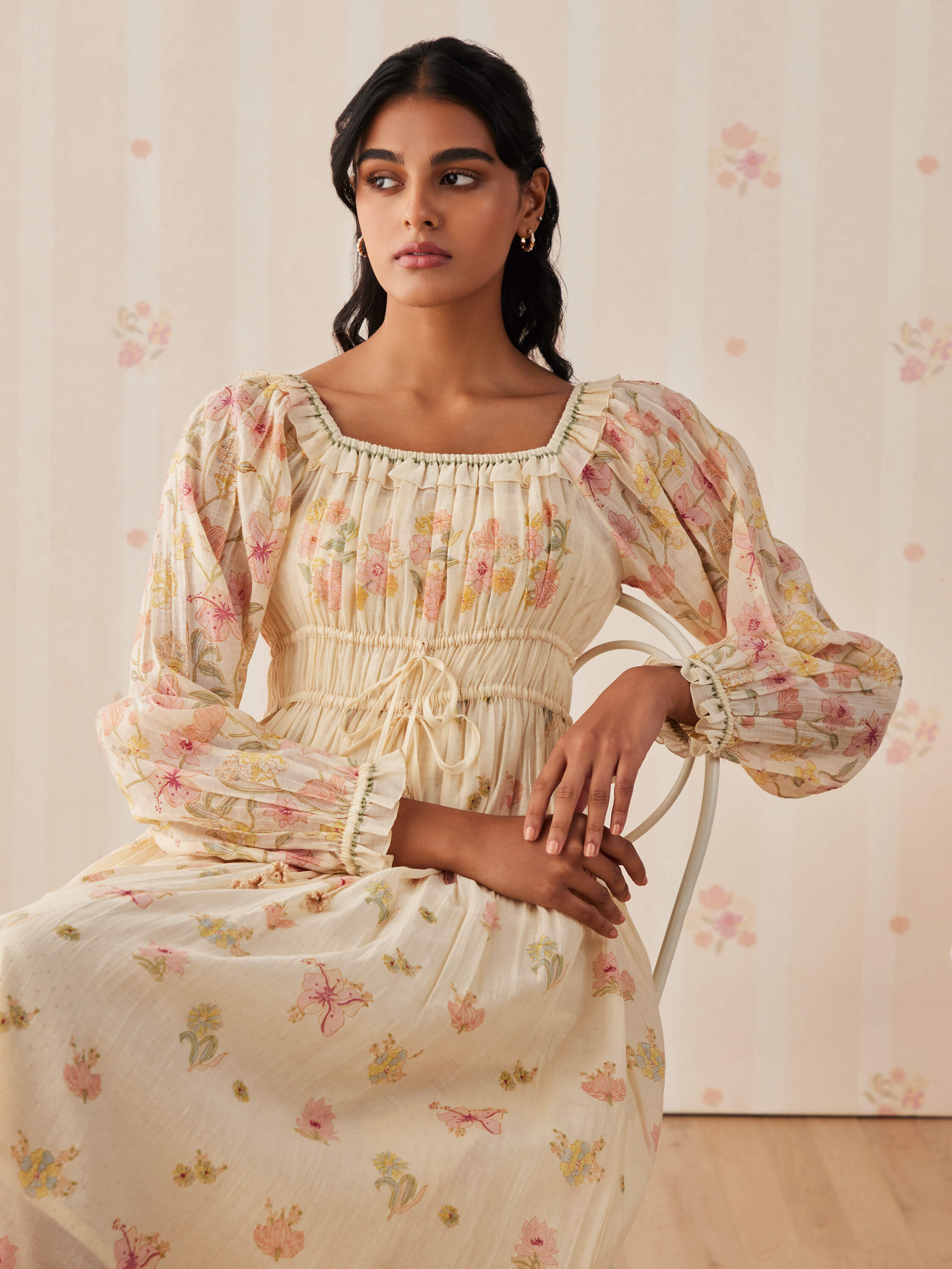 Woman in a floral print dress sitting on a chair.