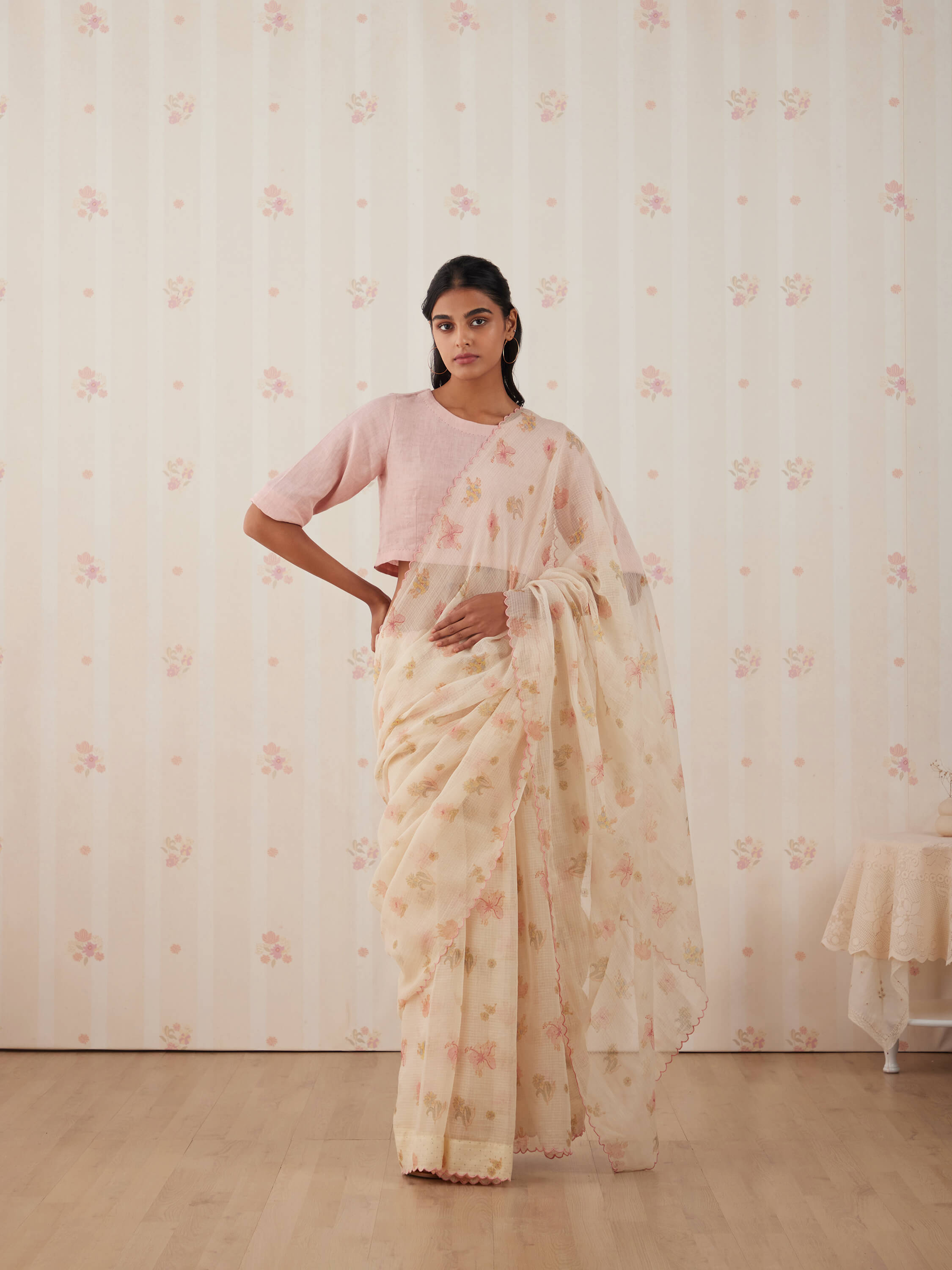Woman in elegant floral saree and pink blouse posing indoors.